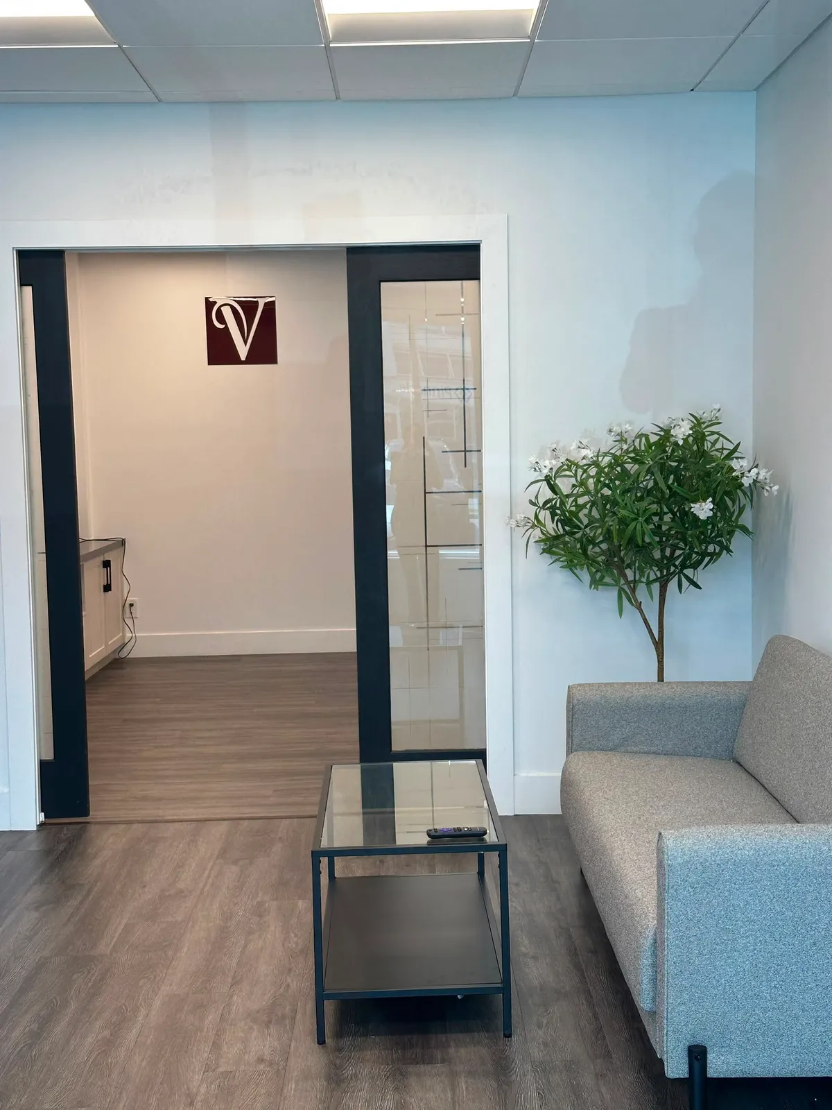 Waiting lounge at Veloura SugarWax Bar with sofa and treatment room entrance